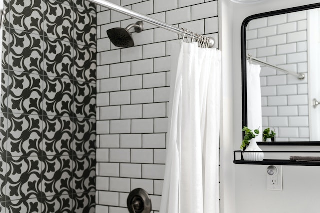 shower curtain rod over tub in white and black tiled bathroom